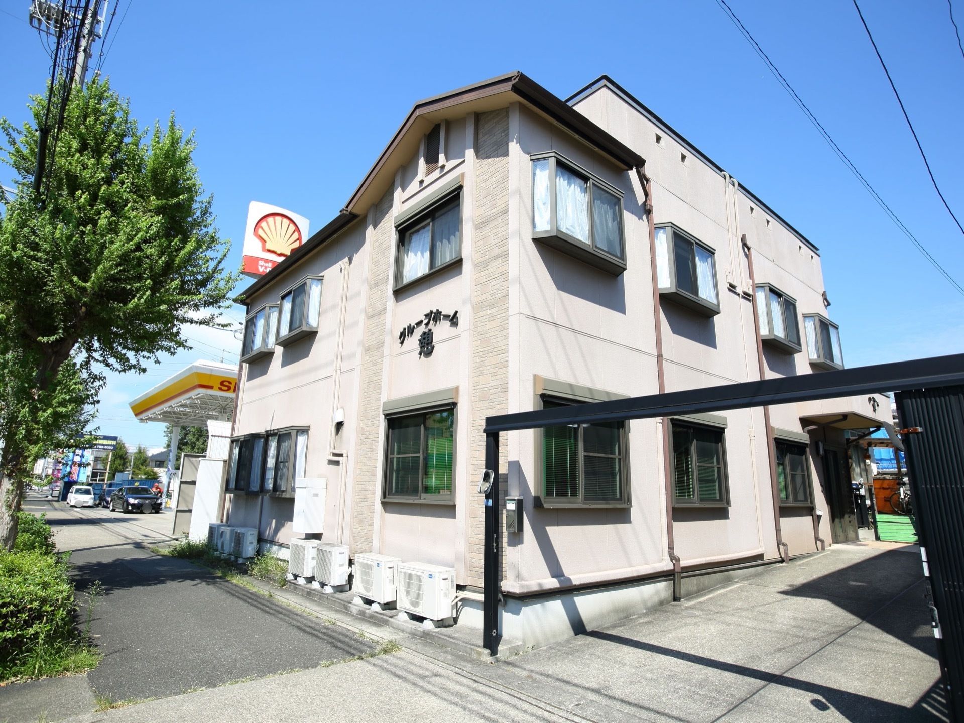 街中に建っているアパート風の外観のグループホーム。外壁の前面にホームの名称が書かれているのが見える。