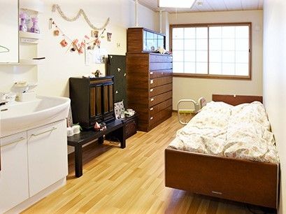 寝具がセットされたベッドが置かれたフローリングの部屋には、大きな窓が付き、タンスや仏壇、洗面所もある。