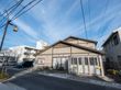三角屋根の２階建ての施設が中央に建っている。施設の前は歩道になっており、街路樹や街頭がある。左手に駐車場がある。