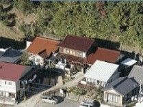茶色やグレーの瓦屋根の家が並び、その後ろには山がある。