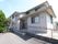 グレーを基調とした２階建ての一軒家風の外観のホーム。玄関の前にスロープと階段があり、緑の木々が植えられている。