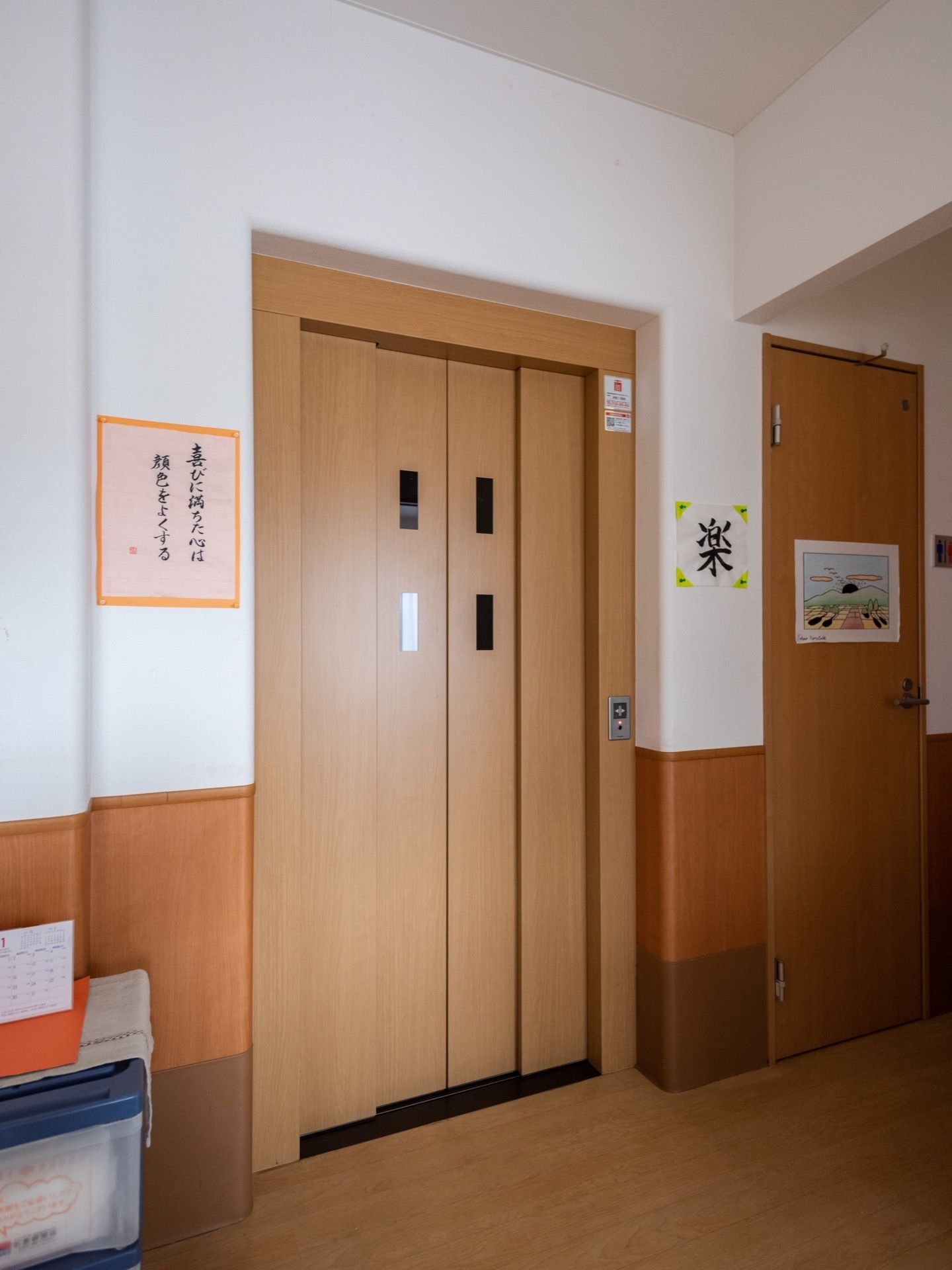 家庭用エレベータが設置されている。外扉は窓付きの両開きタイプで、廊下の内装に合わせて木調である。操作ボタンは右側にある。