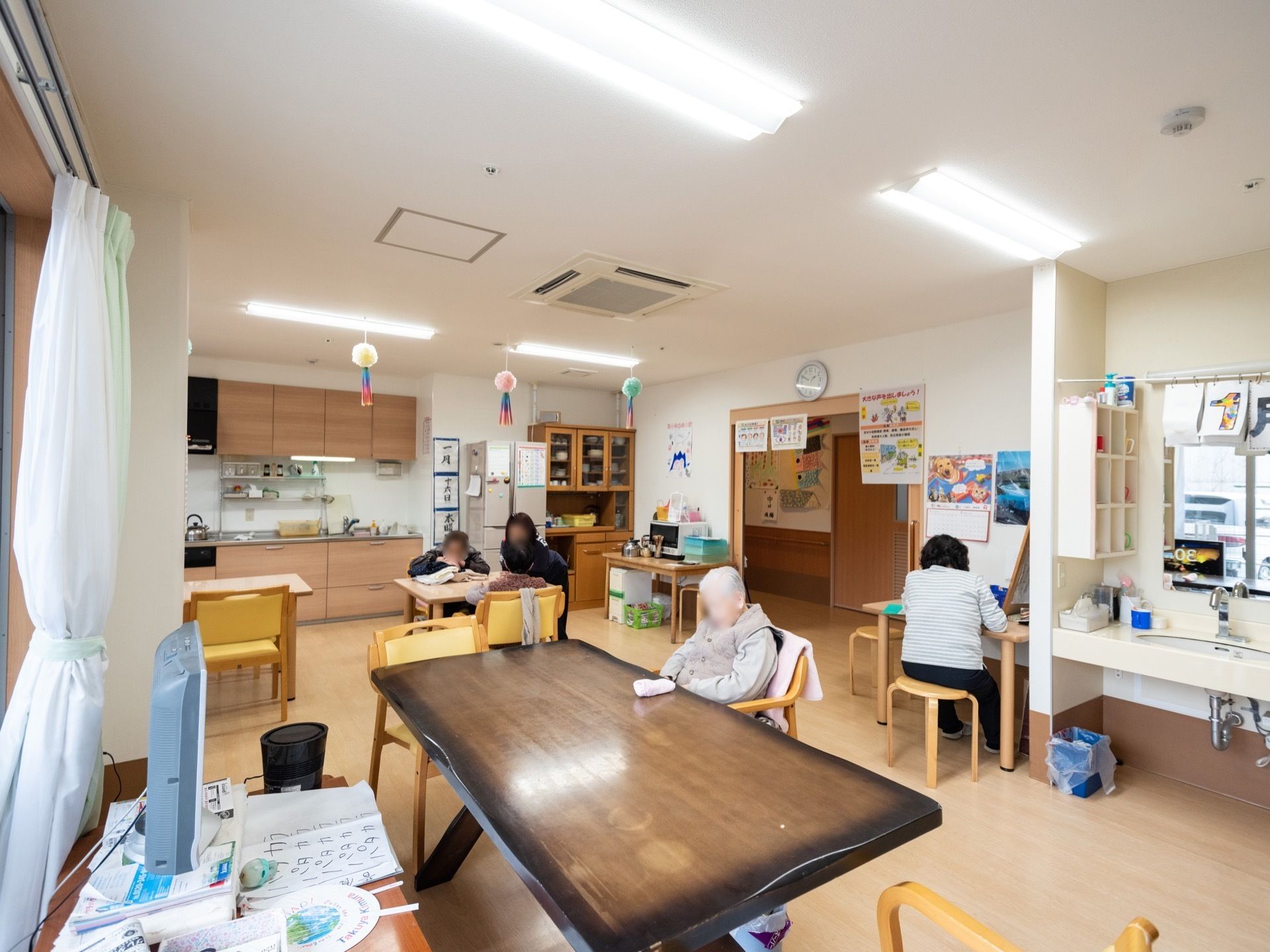 １階の食堂にはダイニングテーブルのほか、スタッフの仕事机や洗面台が設置されている。天井には空調が埋め込まれている。