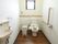 手洗い場が室内に設けられたトイレである。壁にはＬ字型の手すりが設置されており、便器の隣にはゴミ箱が置かれている。