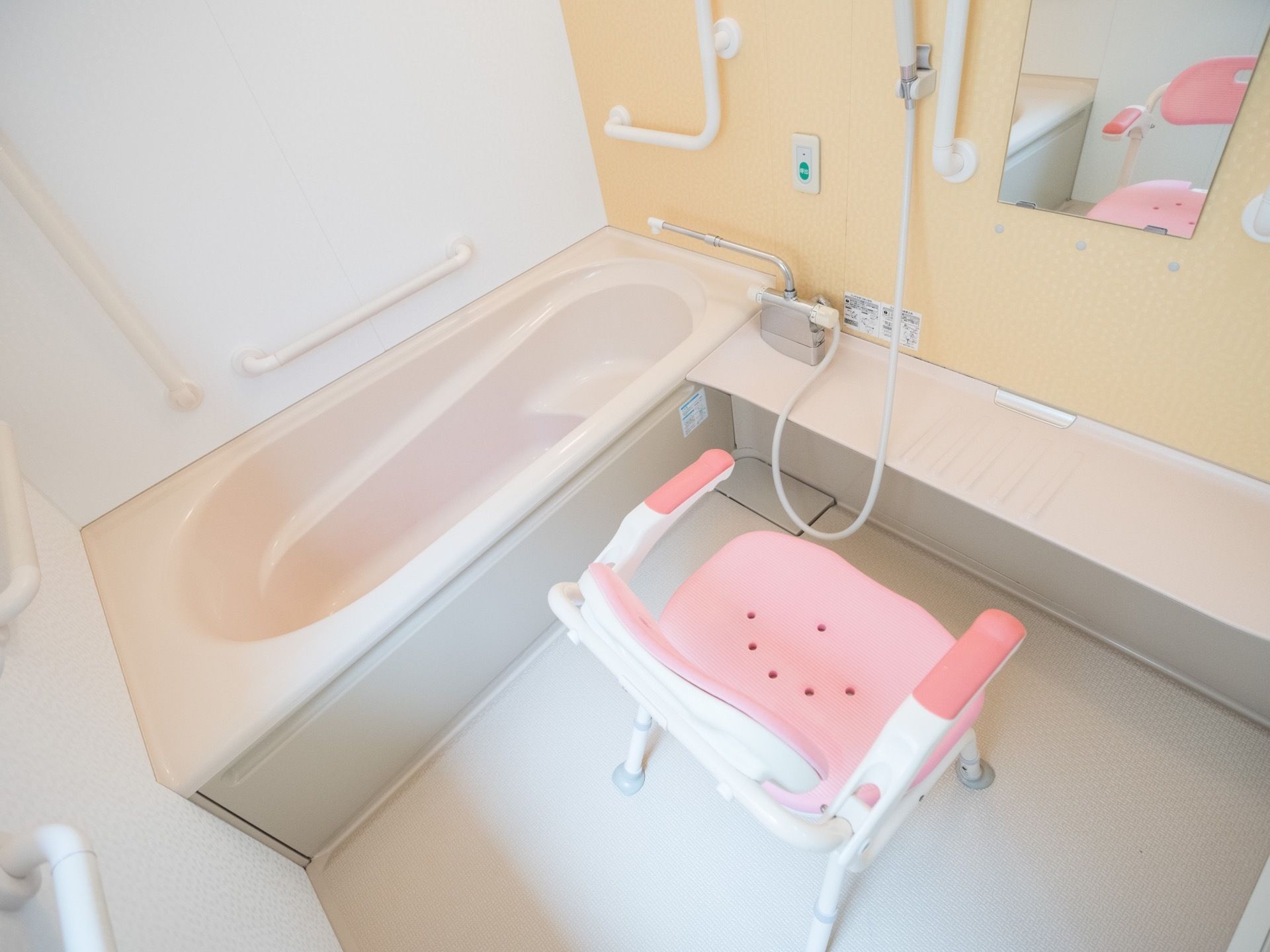 白色を基調とした、明るい浴室である。洗い場には椅子が１脚置かれており、前面の壁には縦長の鏡が設置されている。