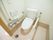 白を基調とした清潔感のあるトイレである。複数の手すりが設置されており、壁にはペーパーホルダーやリモコンがある。