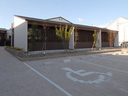 車が止められる広めの駐車場スペースと建物の様子。車いす用の駐車スペースがある