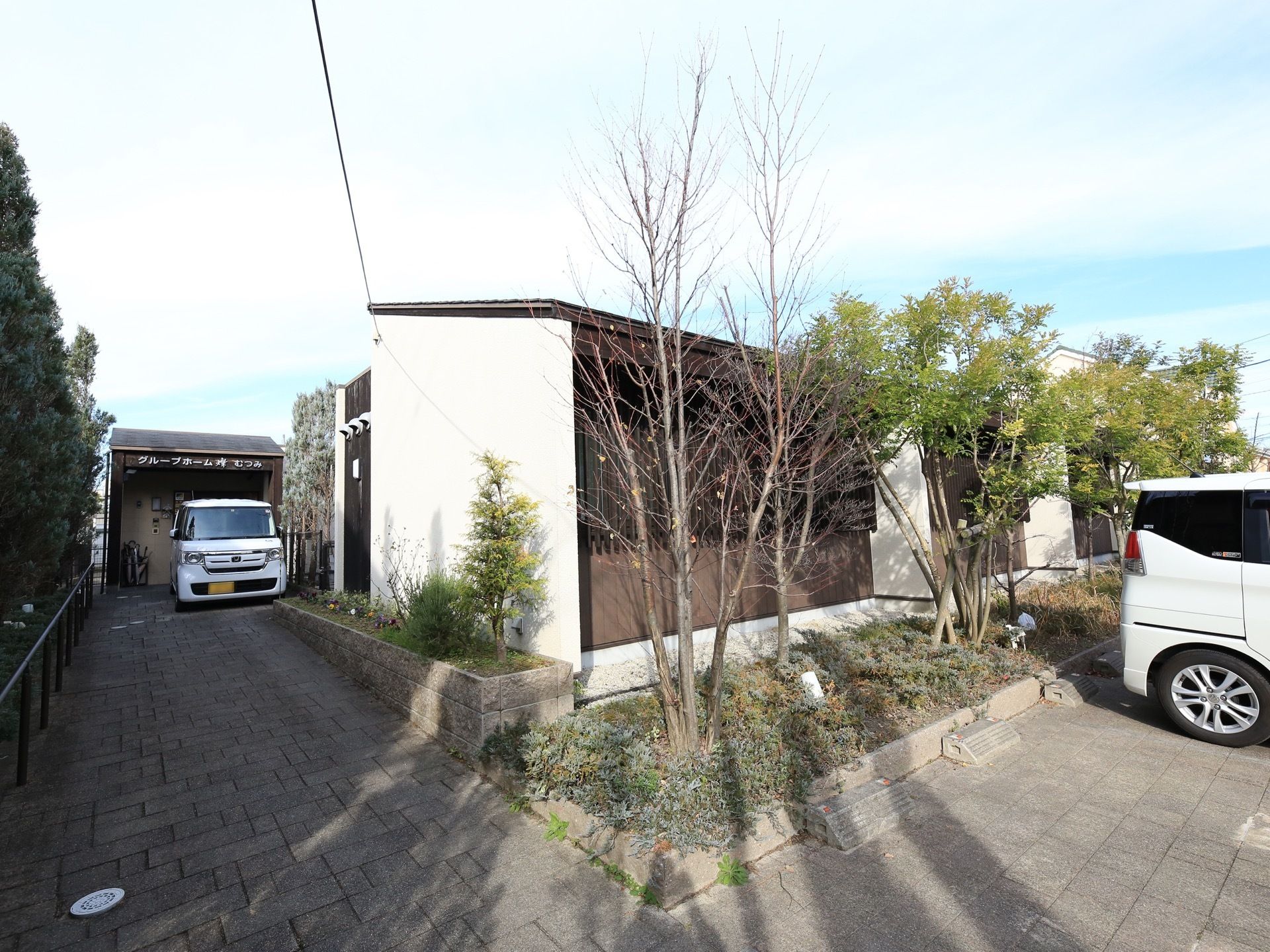 建物周辺は、レンガ造りのモダンスタイルである。駐車場には車輪止めが完備されている。草木がたくさん植えられている。