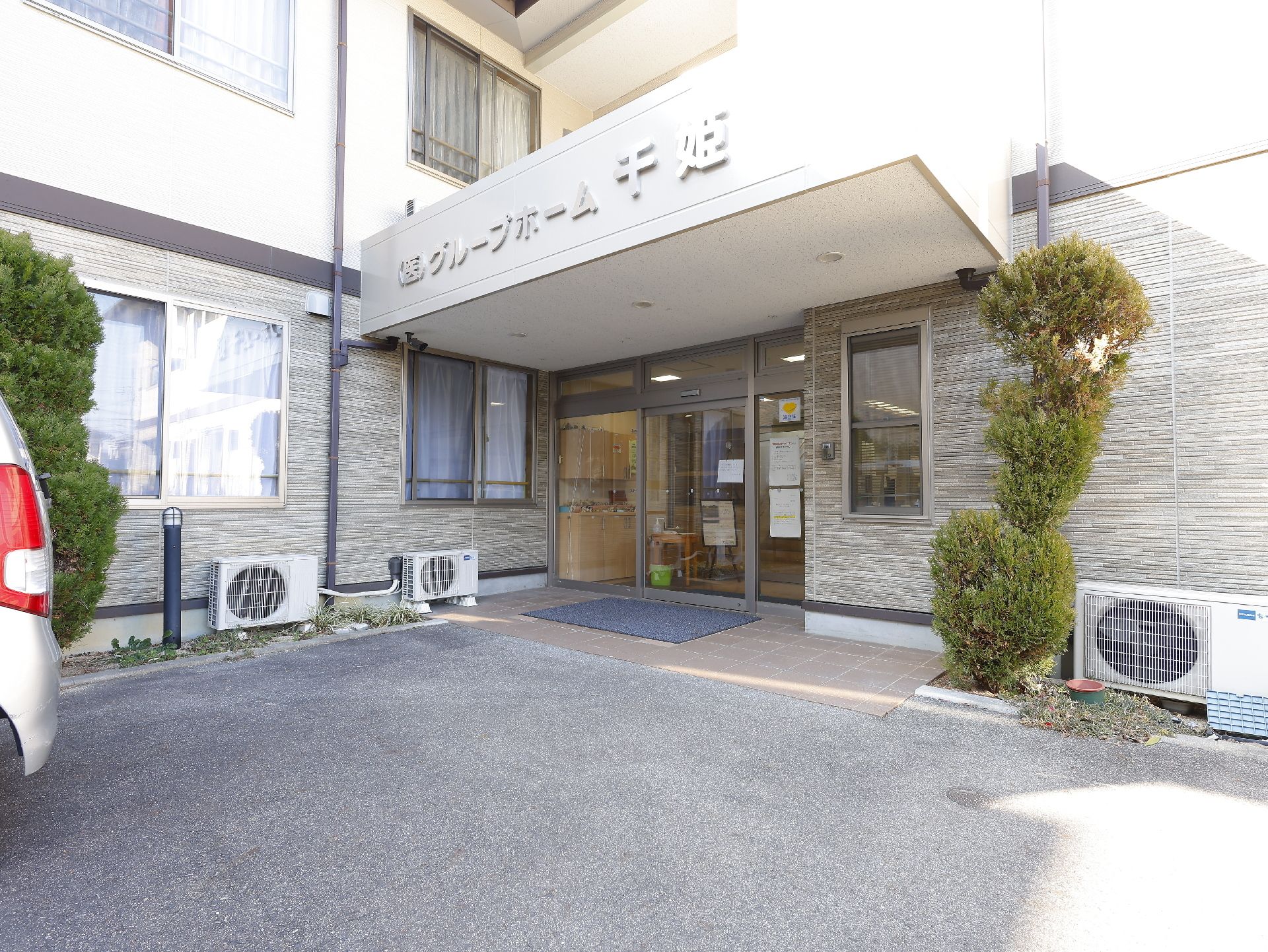 日当たりのいい場所に建っている２階建ての建物はエル字型のブラウン系の建物で、敷地内には駐車場がある。