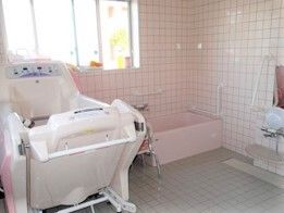 大きな窓が付いた広い浴室。２方向から介助ができる一人用の浴槽と座ったまま入浴可能な機械浴が置かれ、シャワーもある。