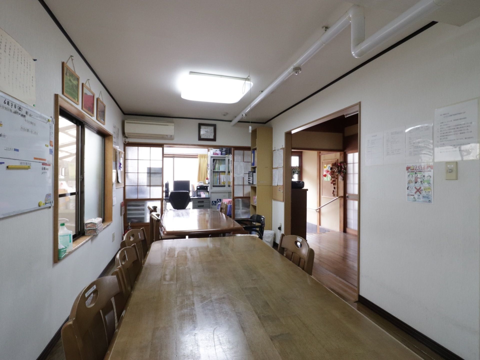 木製の長方形のテーブルが2つ並べてあり、囲むように椅子が置いてある。どこかアットホームな雰囲気である。