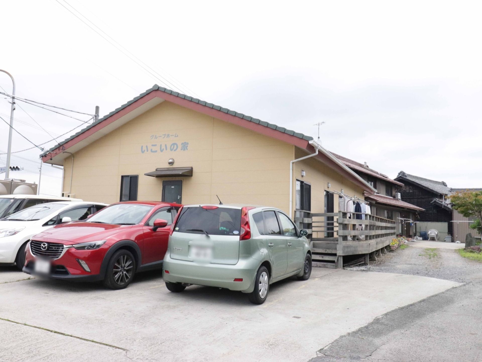 ベージュ色の外壁の建物になっており、平屋建てである。建物の前には駐車スペースがあり、ご家族が車で来訪する際も安心である。
