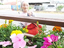 テーブルを囲んで笑顔で話しているポロシャツを着た女性スタッフと白髪の高齢女性。