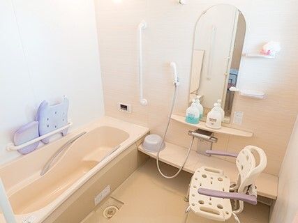 たくさんの手すりが付いた浴室内には一人用の浴槽があり、シャワーやシャワーチェアもある。