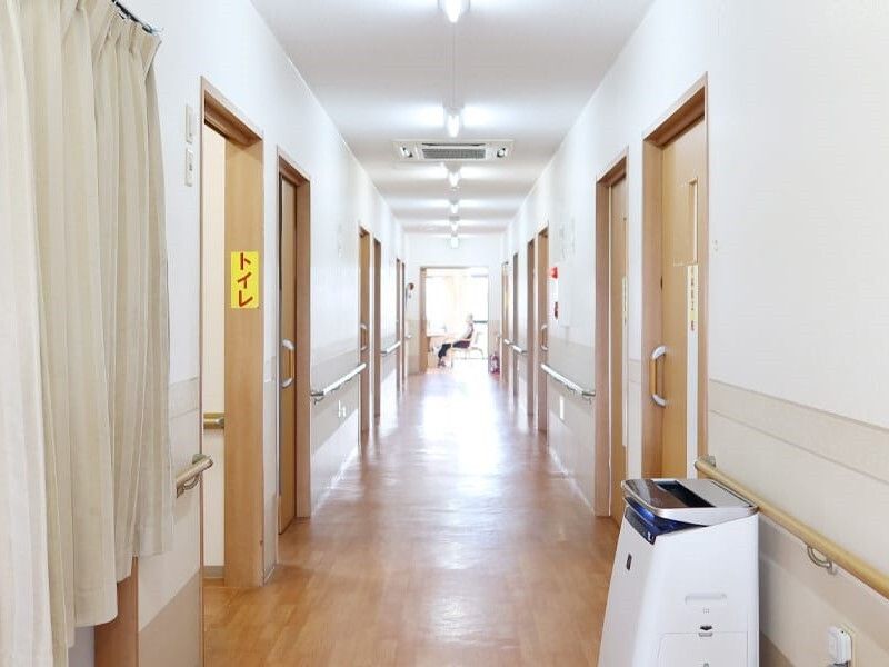 まっすぐな廊下には手すりが付き、空気清浄機も置かれている。トイレには黄色い紙に赤い文字で「トイレ」と書かれている。