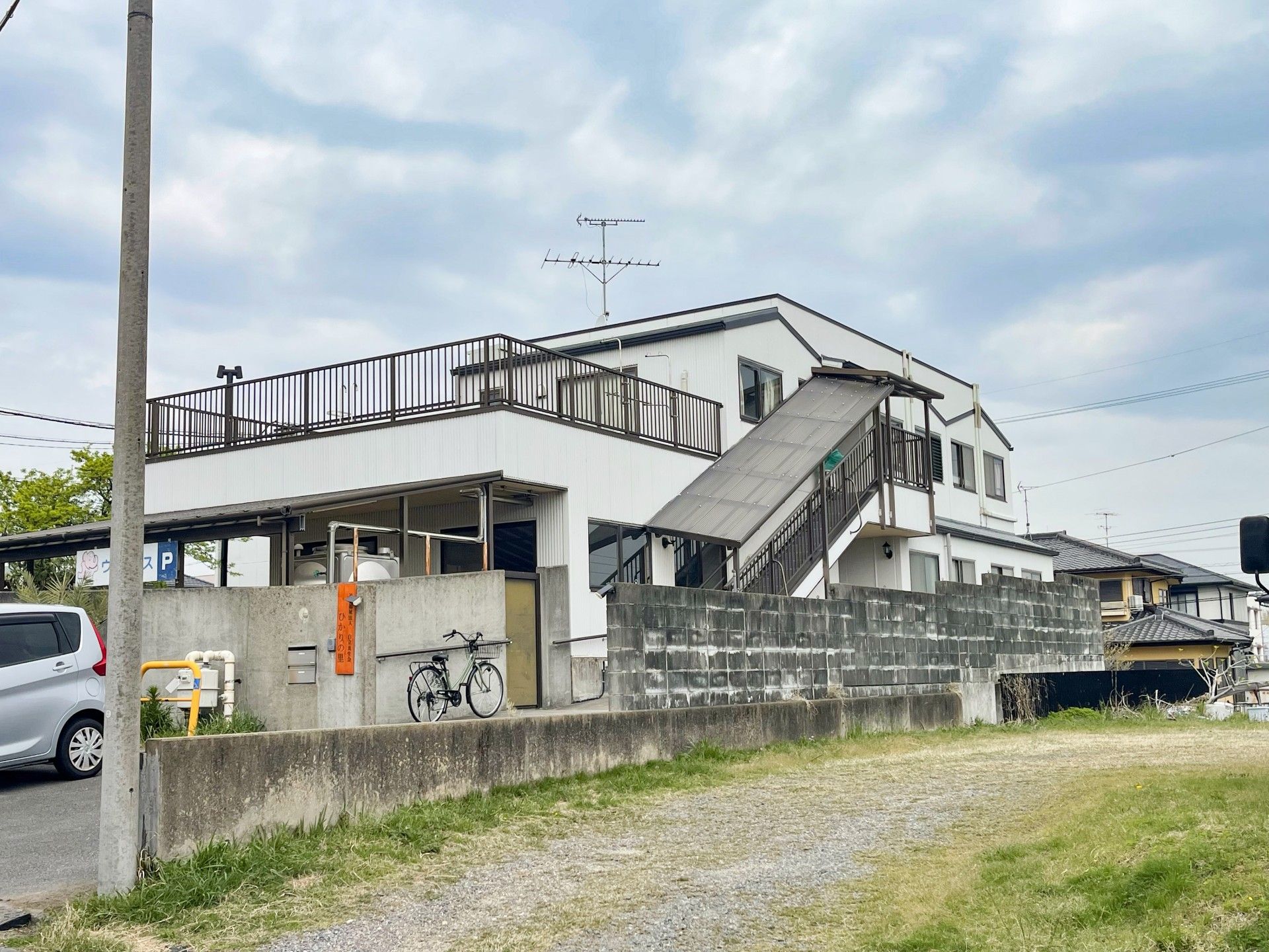 木陰にいる車椅子に乗った高齢男性と付き添う女性ヘルパー
