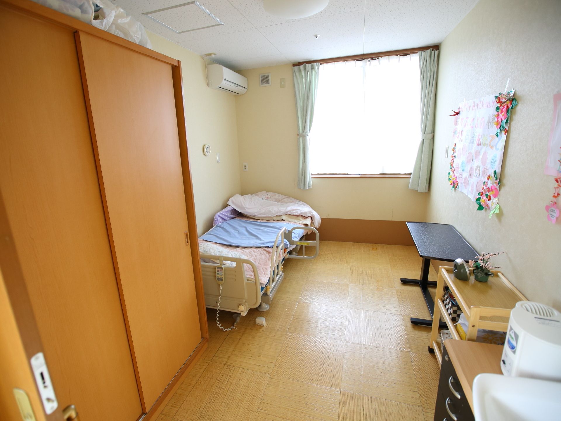 ベッド、タンス、テーブルなどの家具が置いてある居室