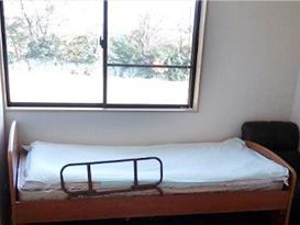 介護用ベッドがおいてある施設内の小さな居室。窓の外に景色が見えているのが分かる