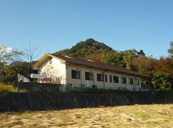 天気が良い日にグループホームゆのやまを写した写真。山々に囲まれた自然豊かな場所