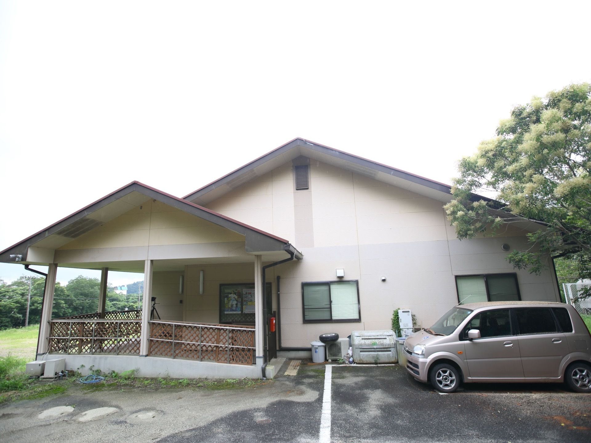 淡いベージュと灰色の外壁の２階建ての建物である。スロープが備え付けられており、段差が解消されている。