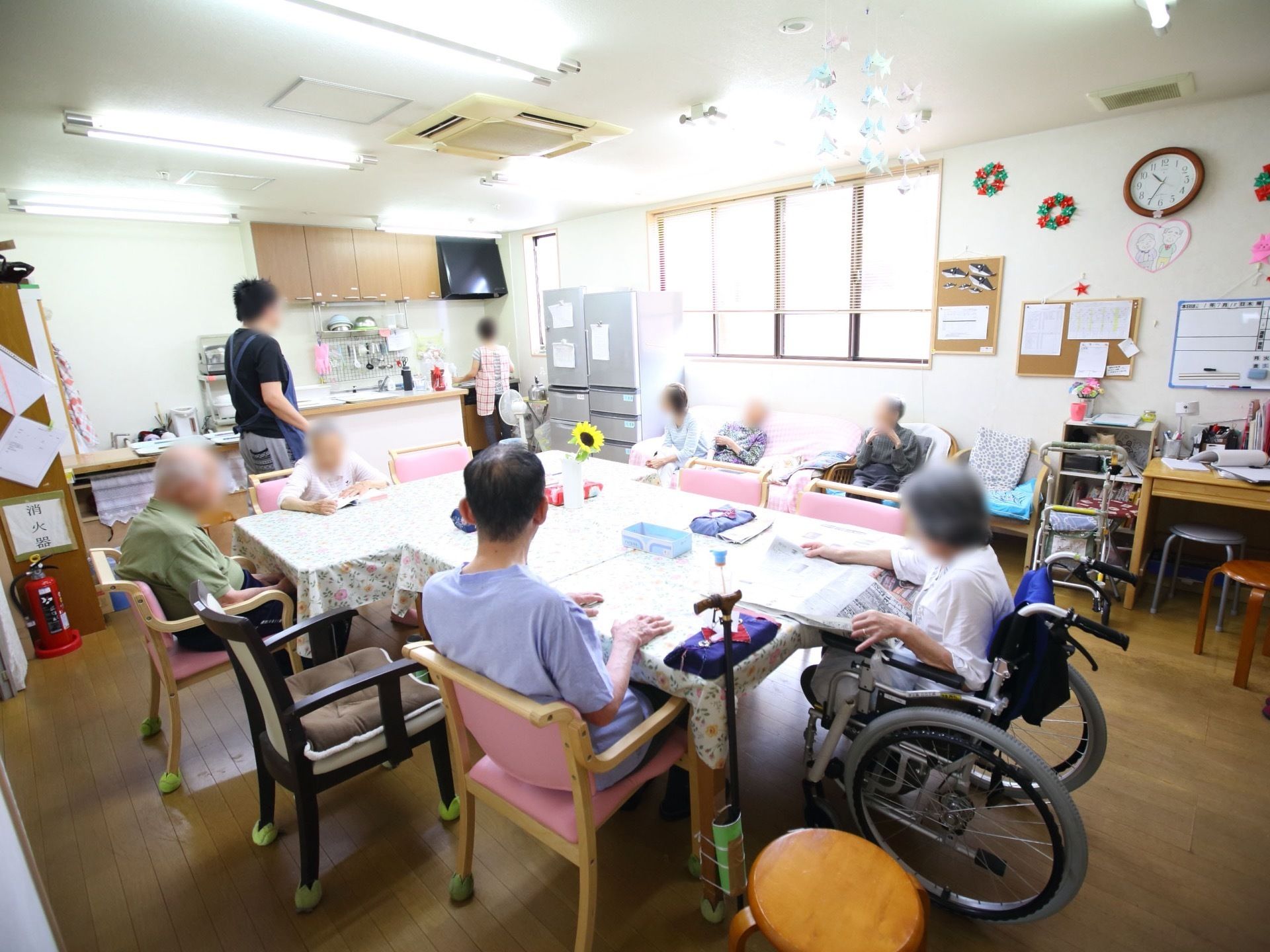 白色と明るい茶色を基調とした、落ち着いた雰囲気の共有スペース。天井には折り鶴、壁には折り紙が飾られている。