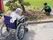 車いすの高齢女性が畑で作業をしているスタッフを見ている様子。奥には田んぼもある。