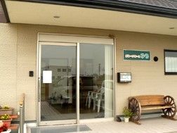 ホームの玄関横には木製のベンチや花が飾られ、アットホームな雰囲気。