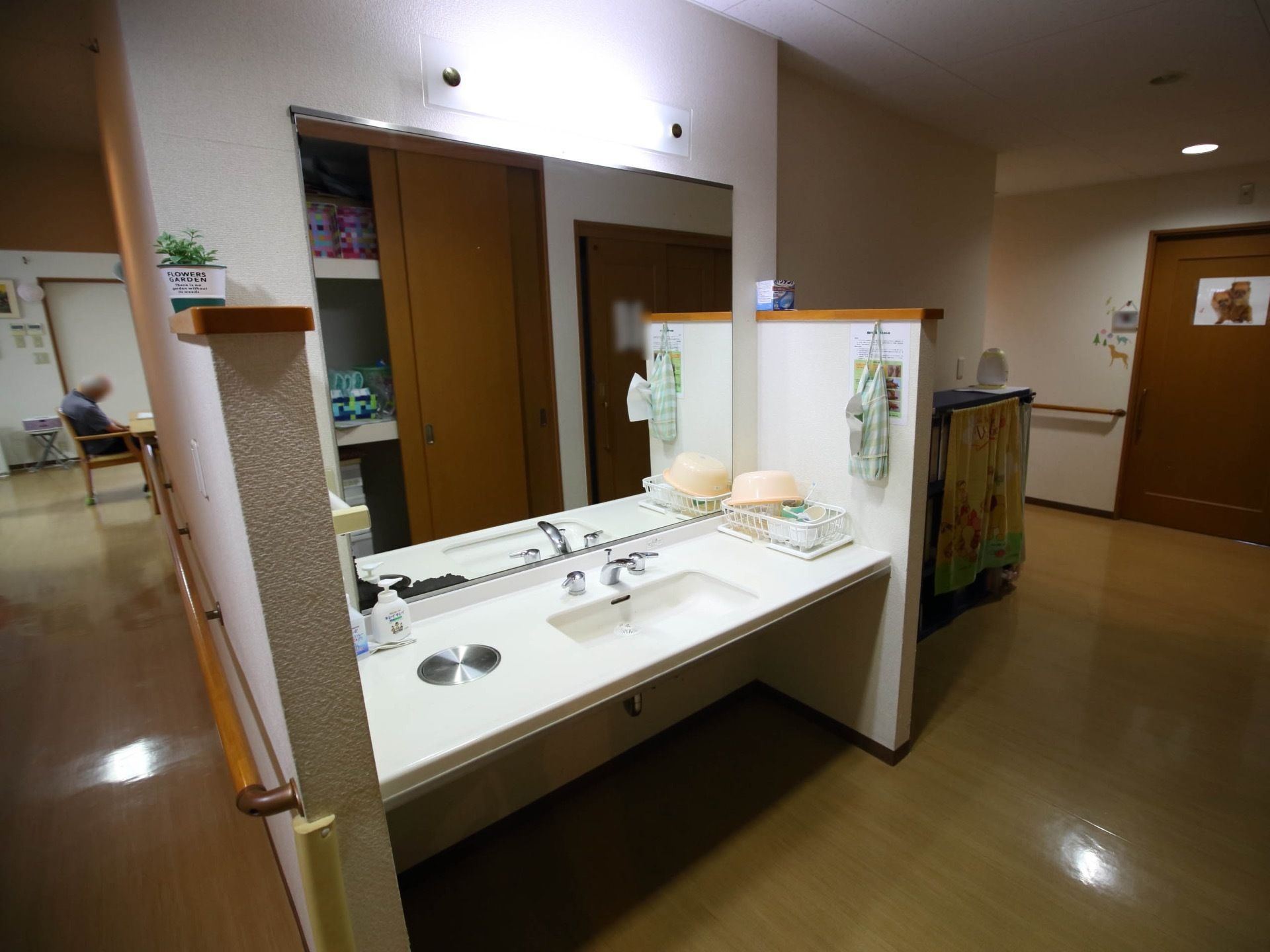 廊下の一角には、洗面スペースが設けられている。車椅子対応洗面台が設置されており、壁に大きな鏡が取り付けられている。