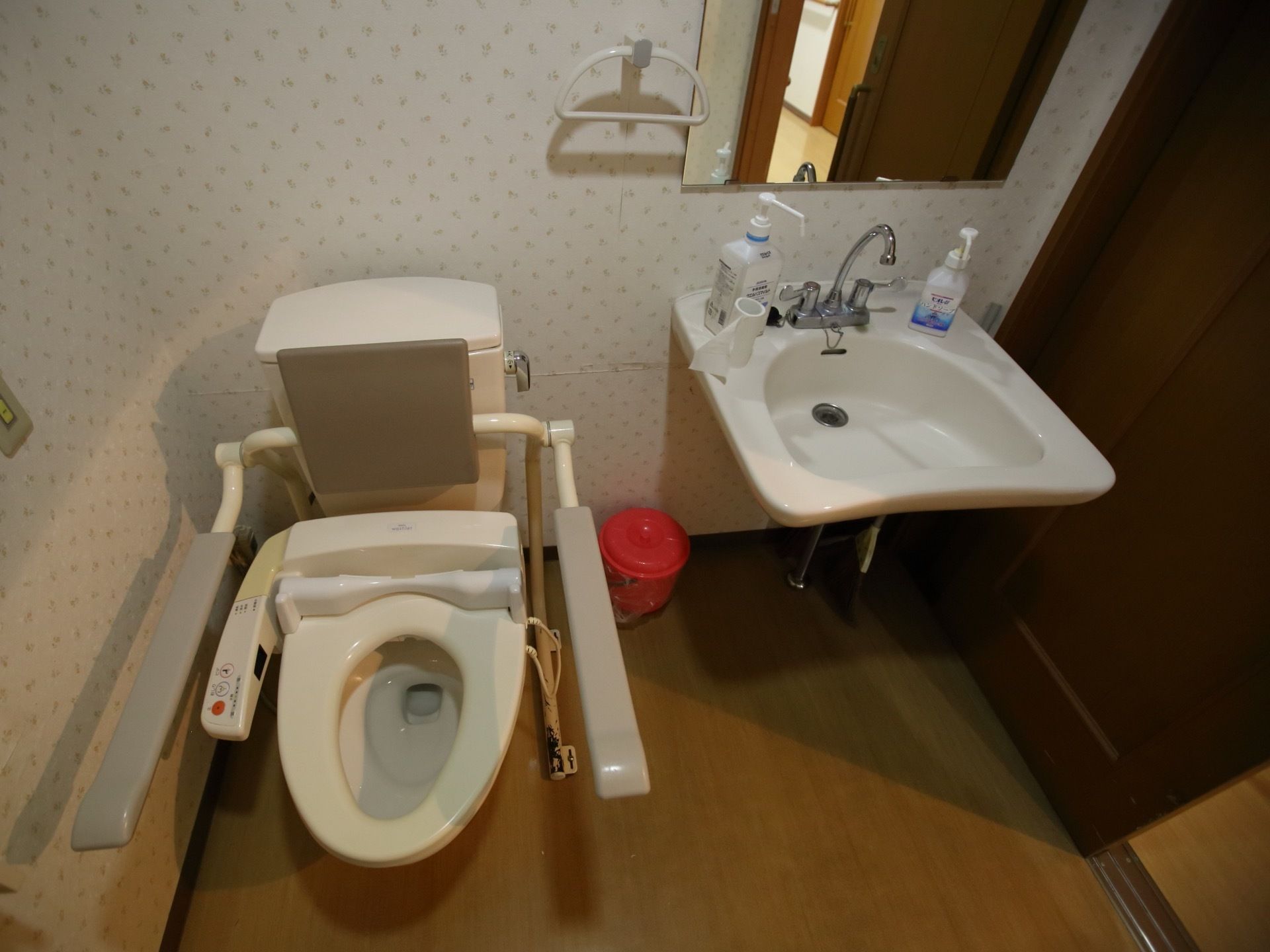 洗面台が完備された広い共用トイレである。洋式便器には、背もたれ付きアームレストが設置されている。扉に引き戸が採用されている。