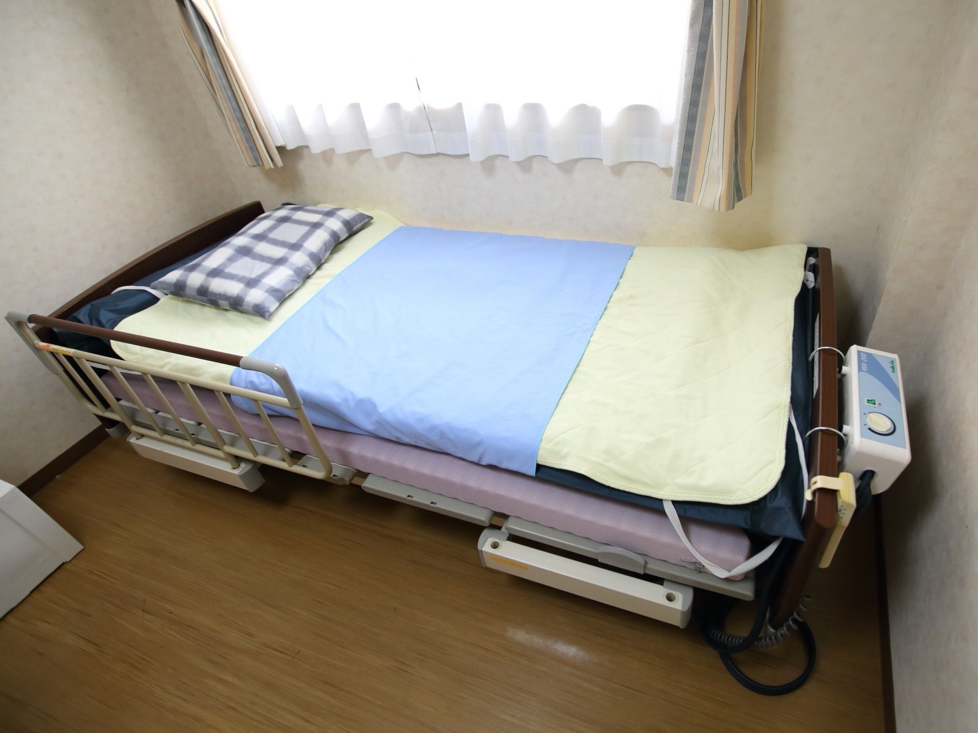 居室には、自然光が差し込む窓が設けられている。窓際に設置された電動介護ベッドには、寝具が用意されている。