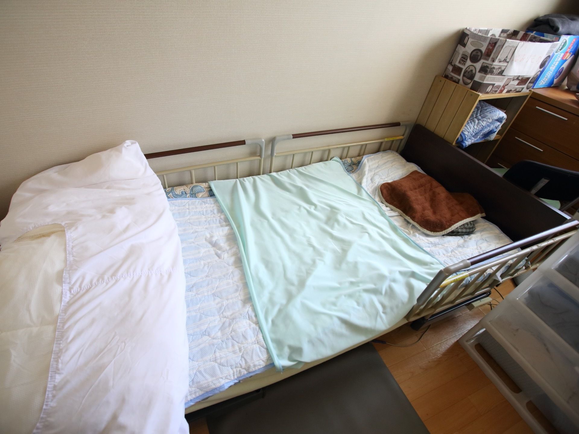 居室には衣装ケースやタンスの他に介護ベッドが置かれている。ベッドの両側には柵が備わっているので、安心して疲れを取ることができる。
