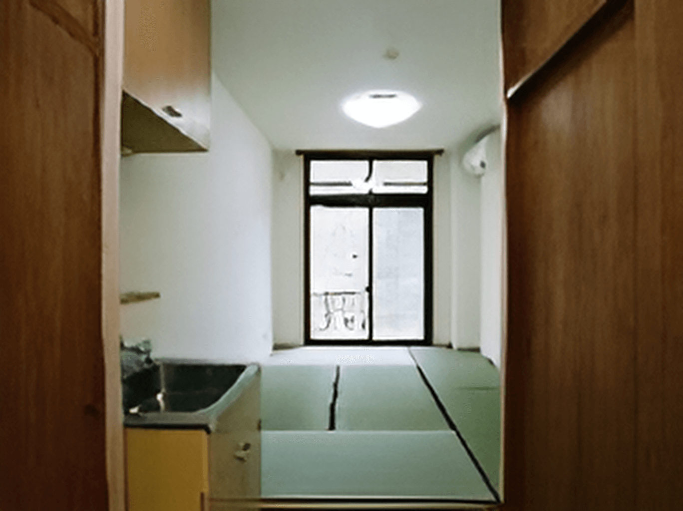 畳敷きの和室の部屋には大きな窓があり、流し台のようなものがあり、家具や家電は置かれていない。
