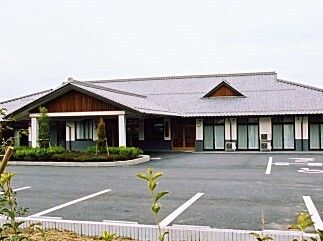 広い駐車場が付いた平屋建ての建物は天井が高く、玄関には三角屋根が付いている。