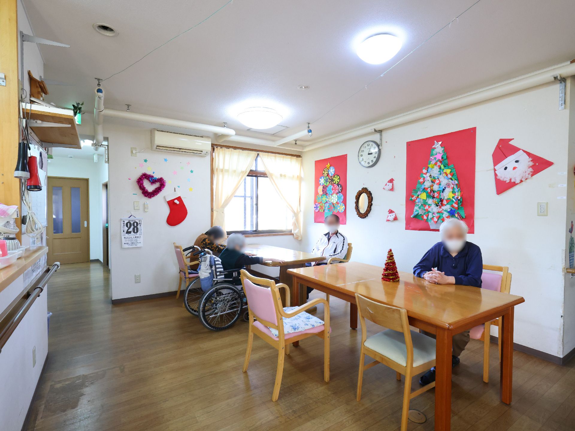 車いすに乗った女性を押す家族の男性とそこに寄り添う介護スタッフの様子