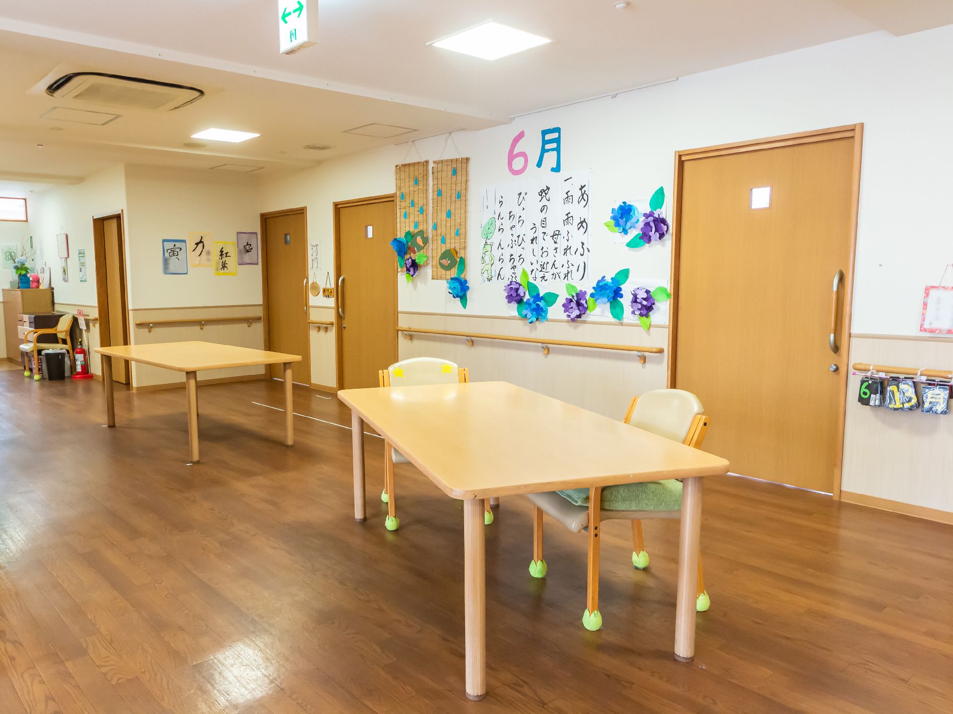 水の入ったコップを持ったエプロンを付けた若い女性スタッフが薬を飲もうとしている高齢女性のそばで待っている。