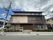 3階建てのブラウン系の大きな建物の上にはホーム名が書かれた看板が立っている。周りには緑も多い。