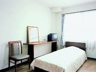 ベッドと椅子が設置された大きな窓のついた居室。