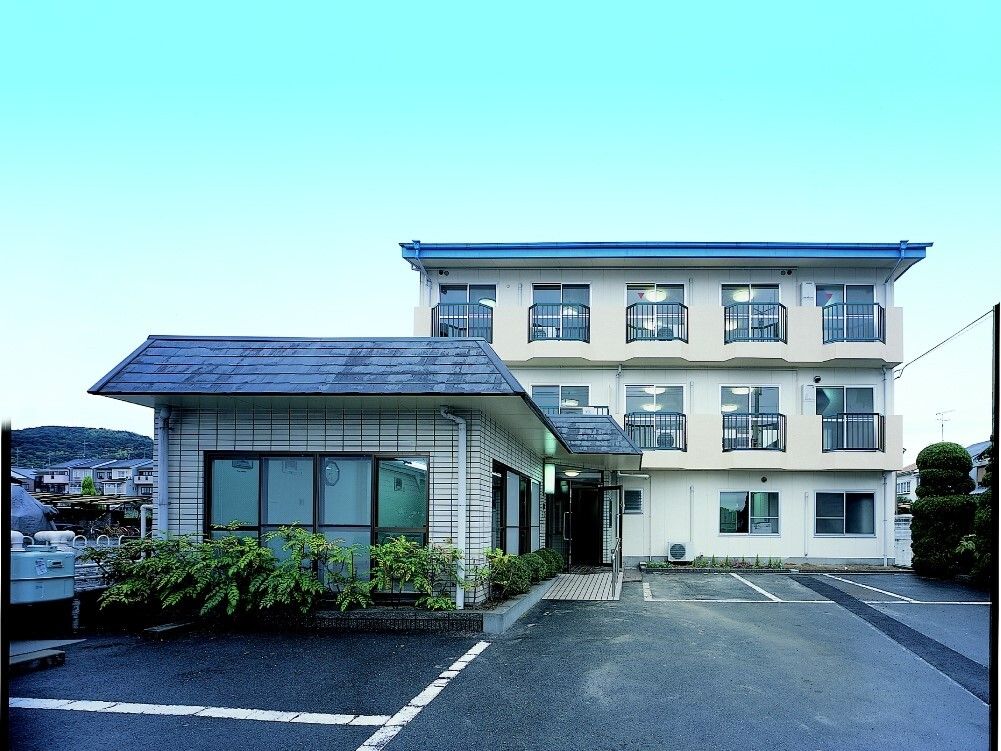 3階建ての建物には窓がたくさんつき、手前には1階建ての建物がある。