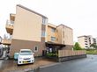 3階建ての茶色い建物と駐車場に停まっている車