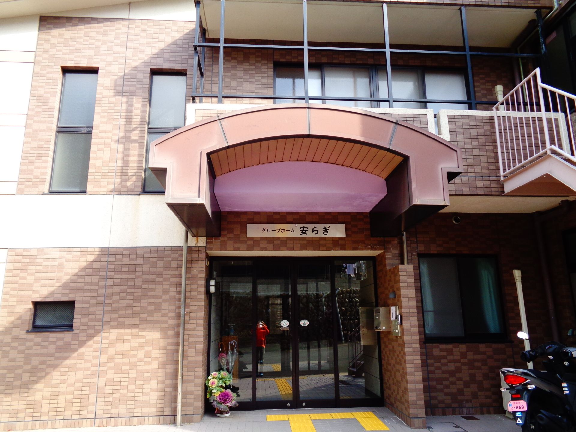 スロープが備わった玄関である。左側に靴箱が設置されている。正面には、昇降機が装備された階段が設けられている。