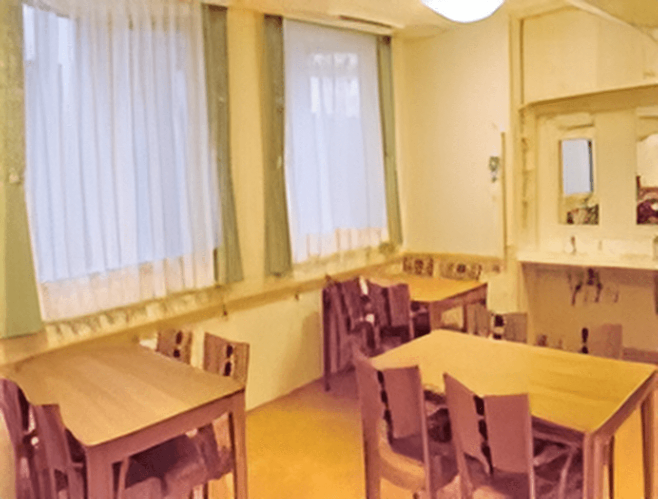 明るい雰囲気のリビングダイニング。木製のダイニングテーブルが複数置かれている。