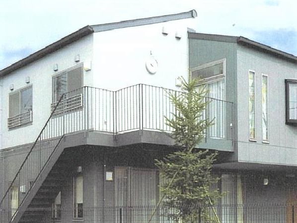 一軒家風の小さな建物の外観。階段の上にある建物