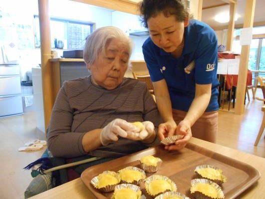 食事の準備をしている様子の高齢者と施設内のスタッフ