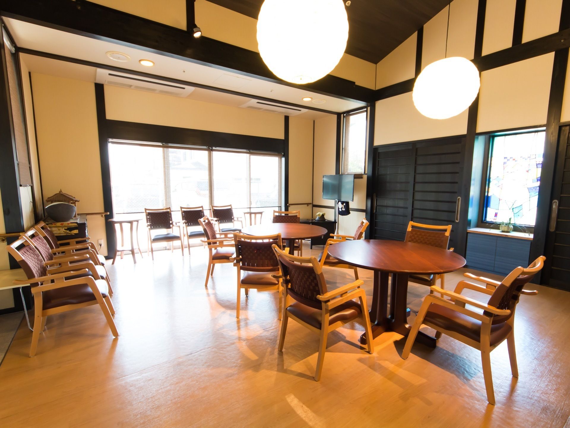 天井の中央が高くなった部屋には、丸いテーブルと椅子を置いている。天井から丸い照明器具がぶら下がっている。