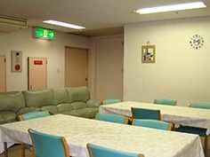 机と椅子が数組、その横にソファが並んでいる施設内の共有スペースの様子