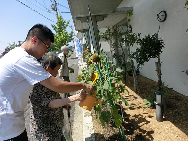 ビニールの使い捨ててぶくをはめてジャガイモを収穫している入居者たち。スタッフも近くにいて話ながら作業している。