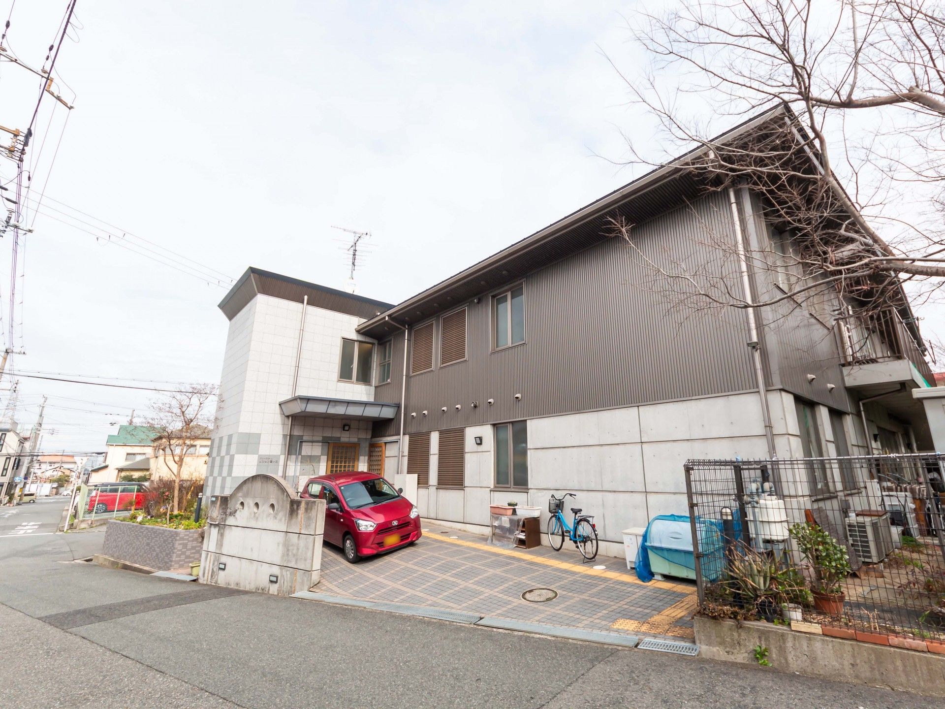 水の入ったコップを持ったエプロンを付けた女性スタッフが薬を飲もうとしている高齢女性のそばにいる。