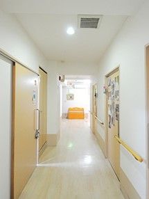 廊下の両サイドに居室と手すりがあり、奥には大きな窓があるため明るい雰囲気。
