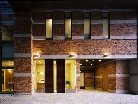 レンガ模様の外壁で、高級感に溢れている。1階のエントランスと2階から漏れる光が暖色で、優雅な印象である。
