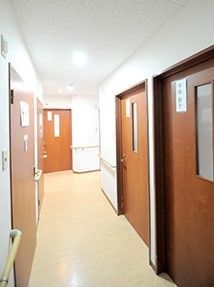 居室のドアはブラウンでよく目立つ。手すりが設置された廊下。